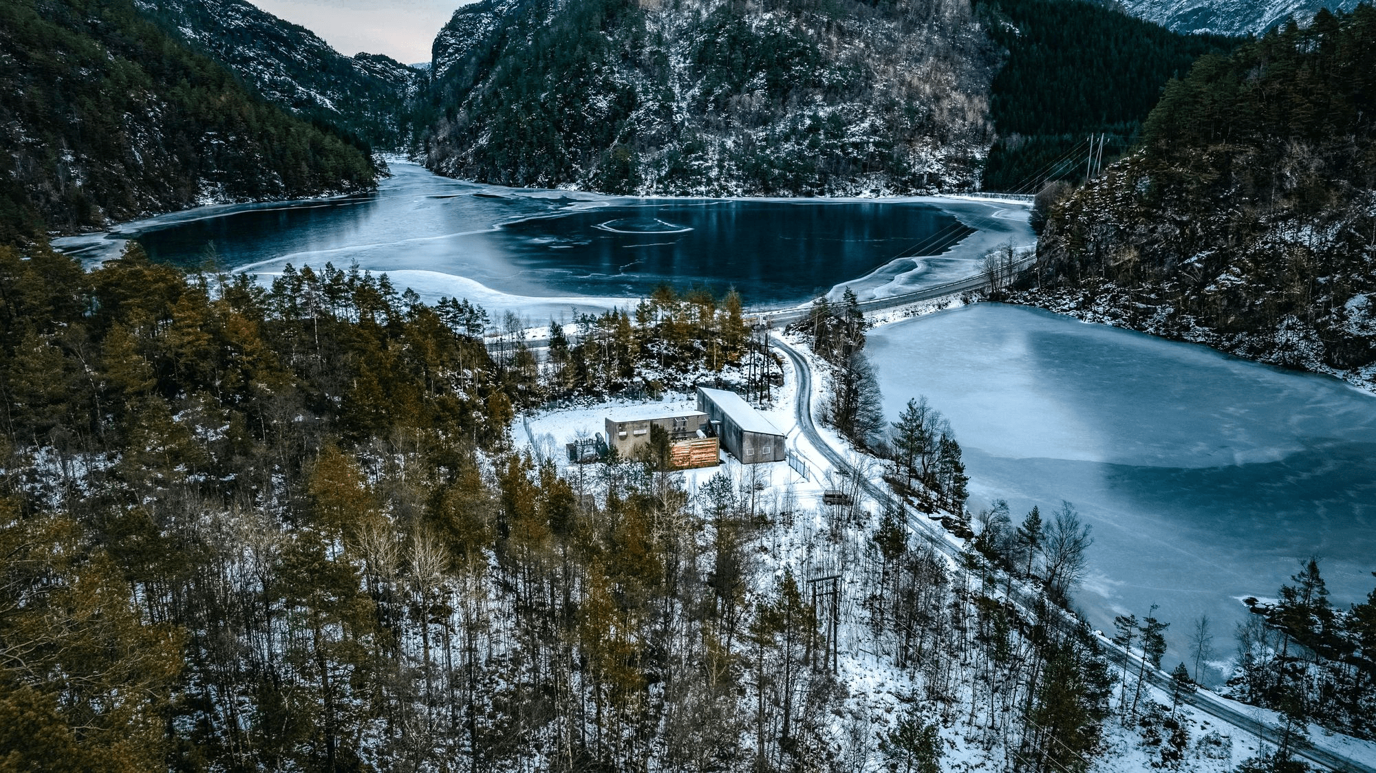 Aerial view of the Suldal site by the lake, between snow-covered hills