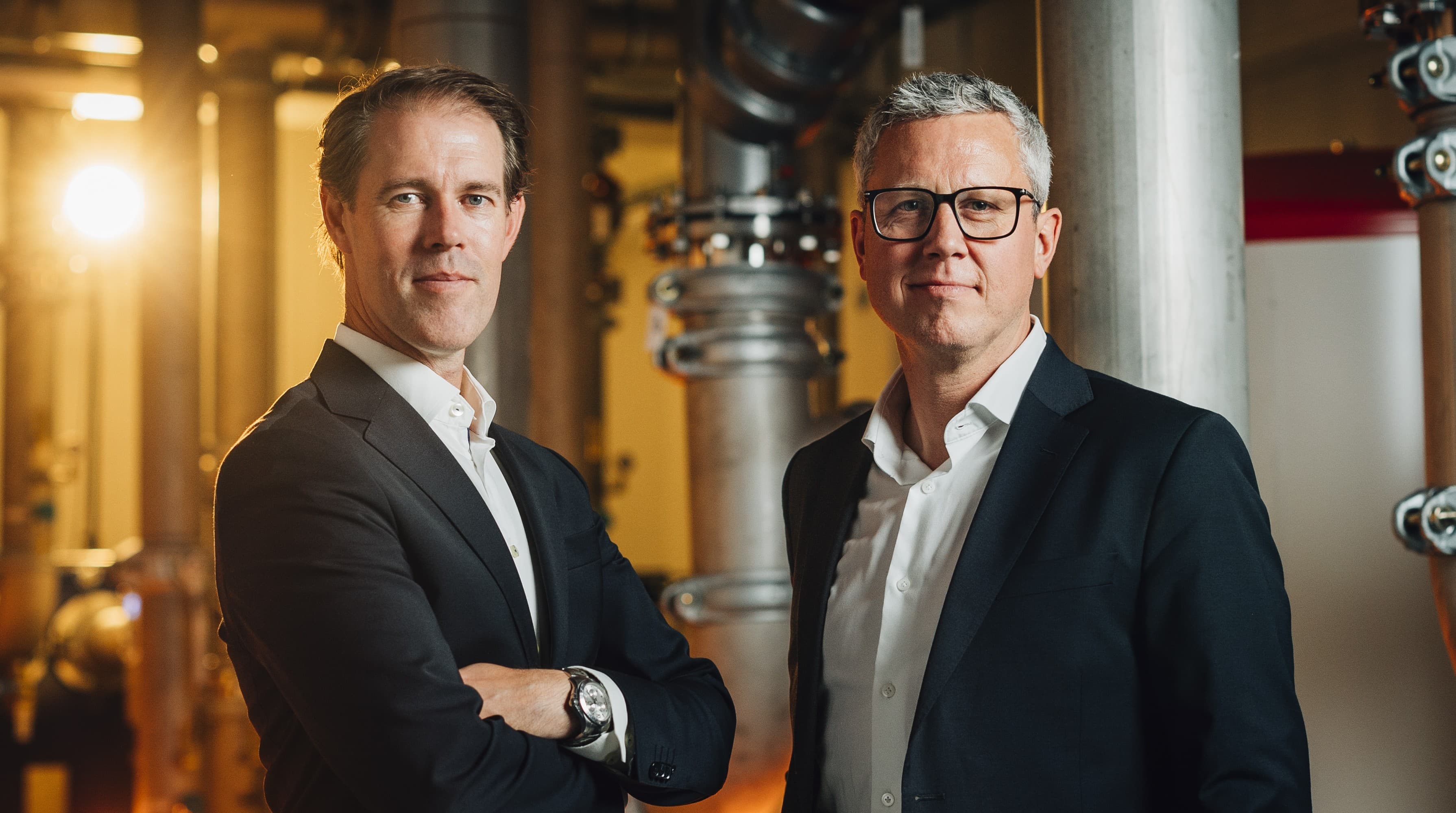 Two Asp Data Center executives standing among pipework inside one of the facilities