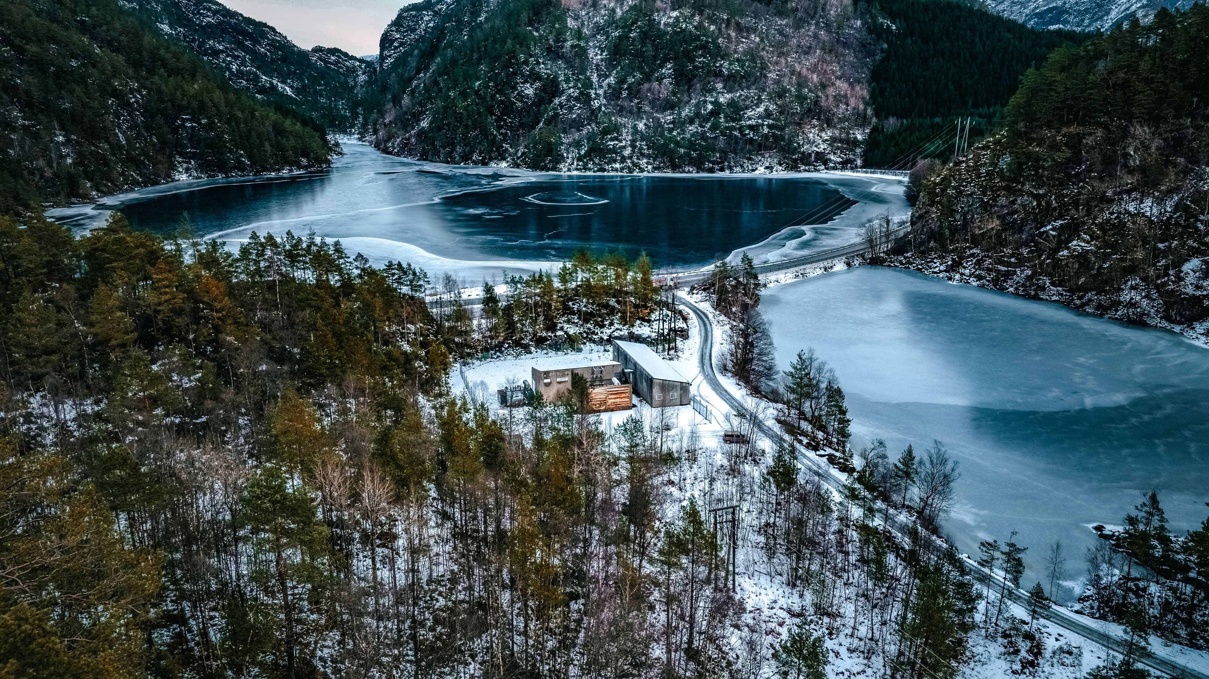 Winter aerial view of the Tysingvatnet site in Suldal, with frozen water and forested hillsides