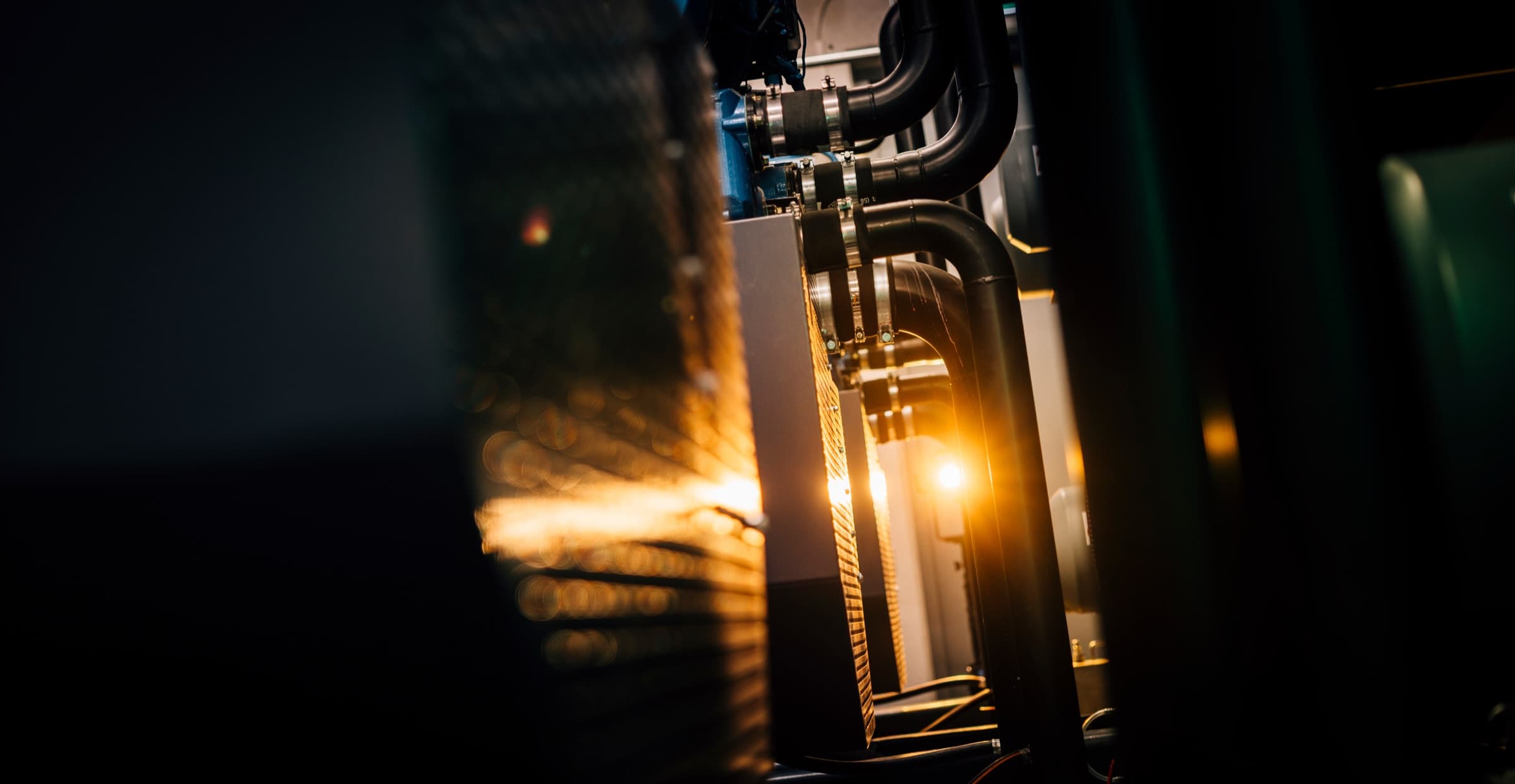 Cooling pipework backlit by warm light in a plant room