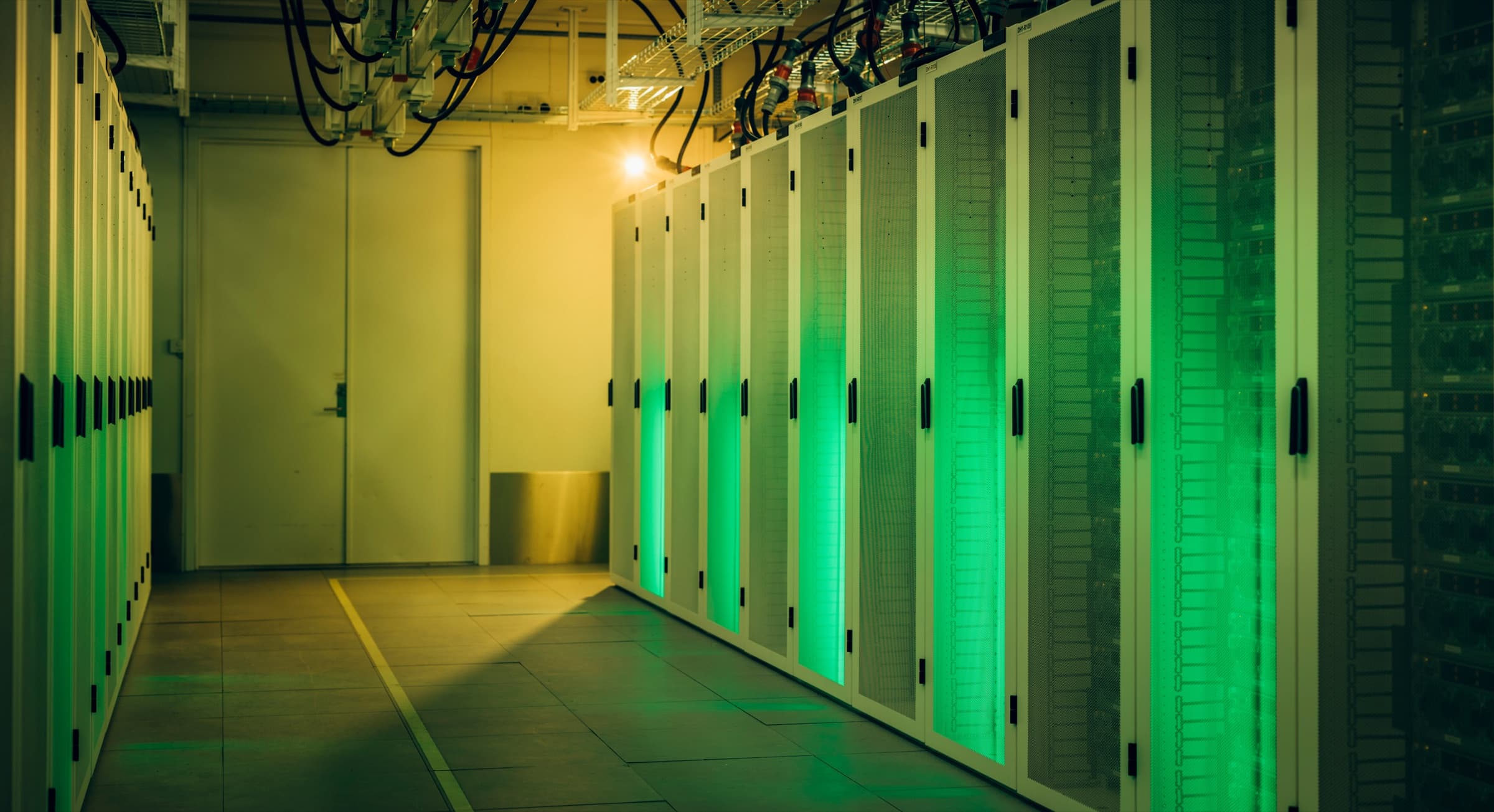 Row of server cabinets glowing green inside a data hall